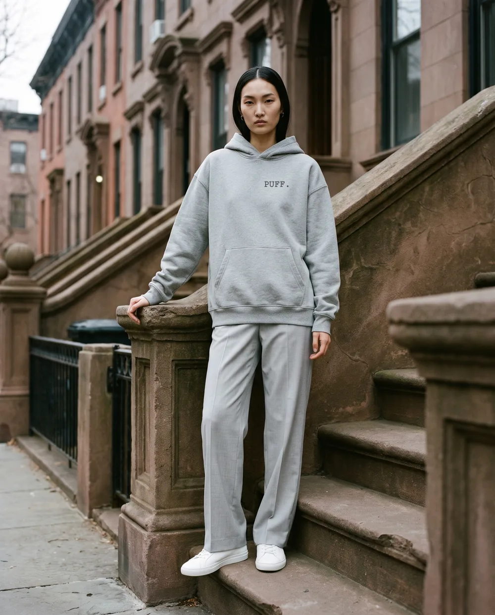 On a brownstone stoop in a heather grey hoodie